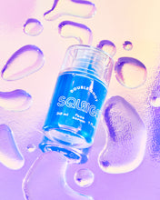 Load image into Gallery viewer, A bottle of a blue face serum with droplets around it.
